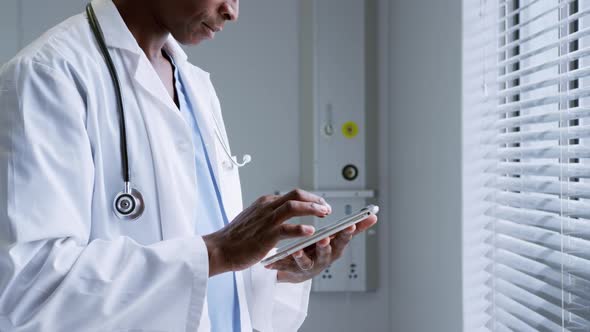 Side view of African American male doctor using digital tablet in hospital 4k alt