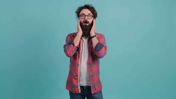 Young Bearded Man Showing Surprise and Amazed Expression with Hands on Face alt