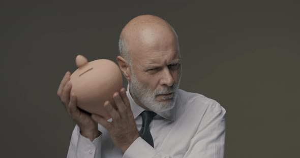Businessman checking his savings in a clay money box