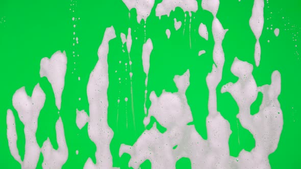 White Soap Suds Flowing Down Window Glass on Green Screen Chroma Key Background alt