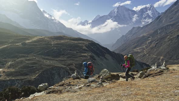 Two Women with Backpacks Are Walking Along the Path in Nepal Mountains. Everest Base Camp Trek. Slow alt