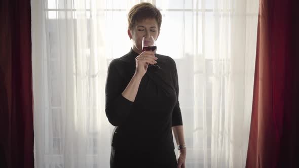 Portrait of Beautiful Woman Enjoying Red Wine in the Evening. Elegant Caucasian Brunette Lady alt