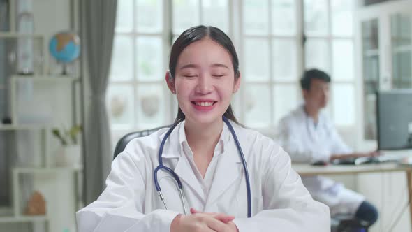 Young Asian Female Doctor Physician In White Medical Uniform Speaking Looking At Camera alt