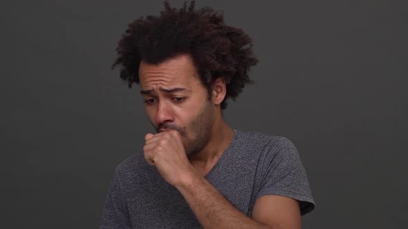 Dark Skinned Man with Afro Haircut Coughing and Choking with Hands on Neck Isolated Over Charcoal alt
