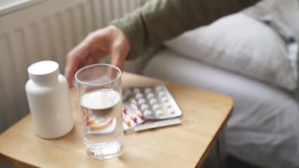 Bedside Table with Pills and a Glass of Water Closeup alt