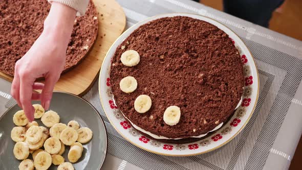 Woman Putting Pieces of Sliced Banana Preparing Delicious Chocolate Banana Tart alt