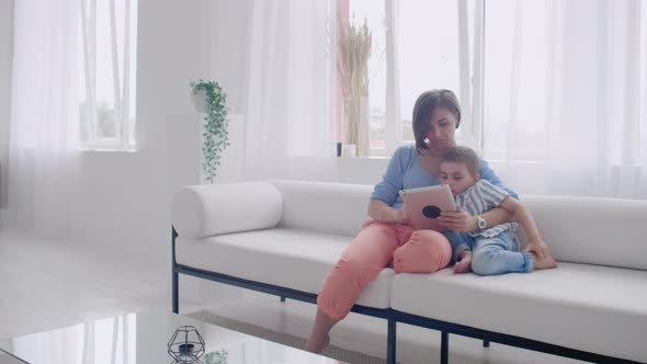 Mother and Son Sitting on Sofa Using Digital Tablet alt