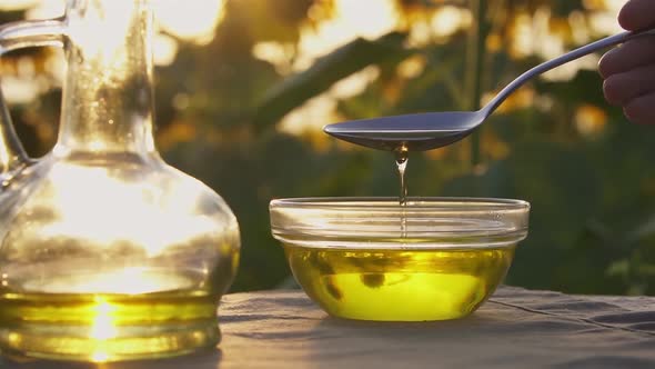 Ingredients For Cooking Sunflower Oil. Oil Slowly Pours From A Spoon Into A Glass Bowl alt