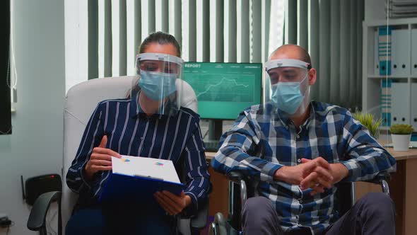 Man in Wheelchair and Coworker with Visor Having Videomeeting alt