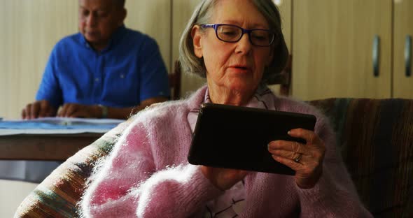 Senior woman using digital tablet in living room 4k alt
