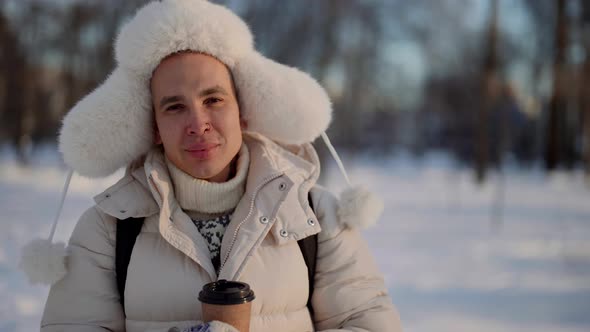 Handsome Guy in Winter Clothes and Warm Russian Ushankahat is Walking in Park Trapper Hat alt