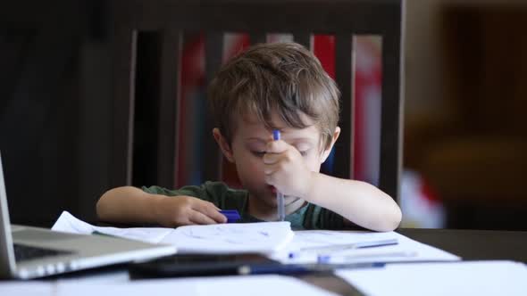 Little toddler boy is playing with pens on father's working place at home