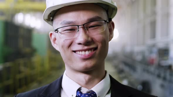 Smiling Asian factory manager staying at manufacture