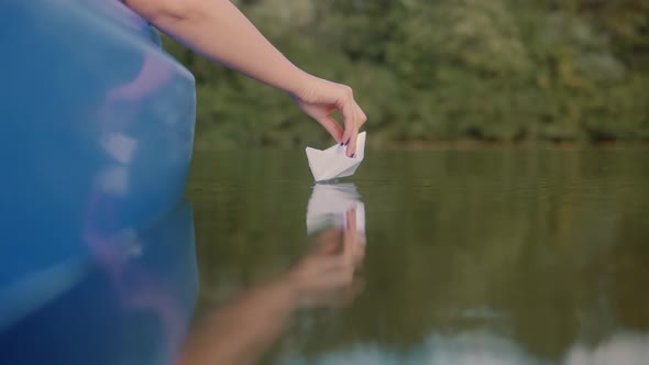 Handsome Girl Launching Origami Ship In Water On Sunset. Relaxing And Enjoying Time. Paper Boat. alt