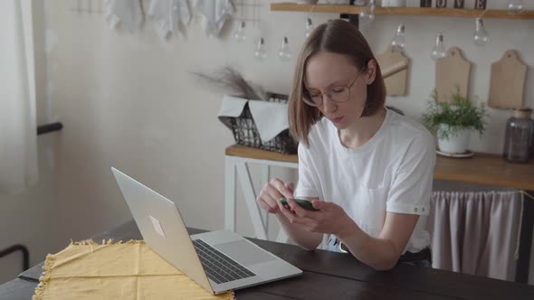 Caucasian Young Woman Shopping Online with Smartphone Enjoying Break During Work in Front of Modern
