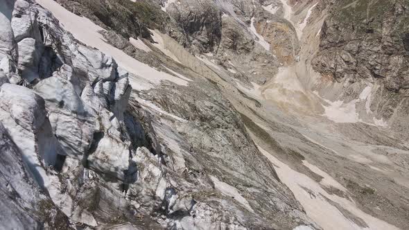 Glacier Covered with Stone Rocks Deep Cracks and Small Waterfalls alt