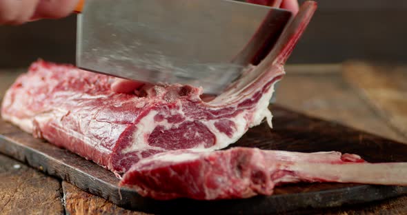Men's Hands with a Knife Cut Raw Rack of Lamb Into Pieces.  alt