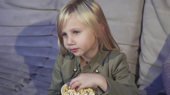 Cute Little Girl Eating Popcorn Smiling To the Camera at the Cinema