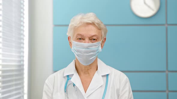 Cheerful mature lady doctor with grey hair in coat with stethoscope alt