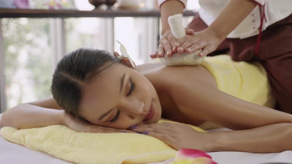 50p frame rate footage of  Woman lying in bed for Thai Traditional Massage, using the compress.