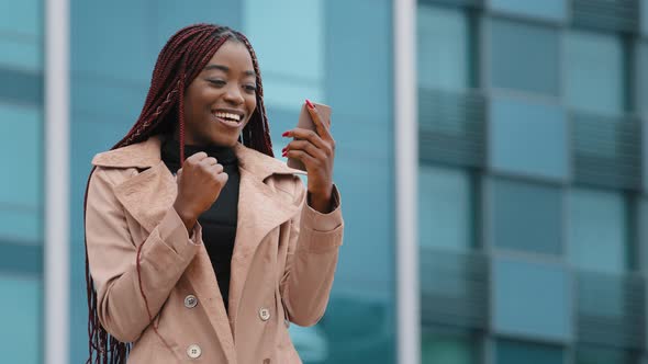 Happy Millennial African American Woman Standing Outdoor on Modern Building Background Holding alt