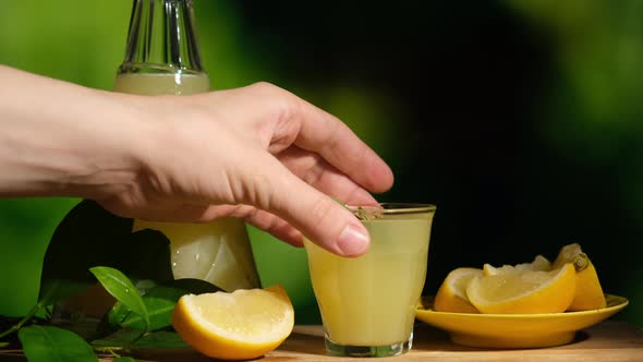 Hand Takes a Shot Glass of Limoncello Drink alt