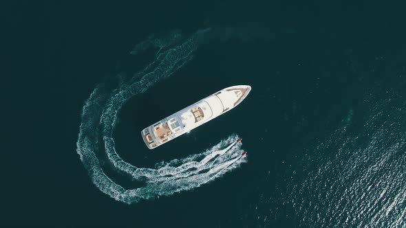 Aerial view of two Jet Ski ride around Super Yacht at Sunset.