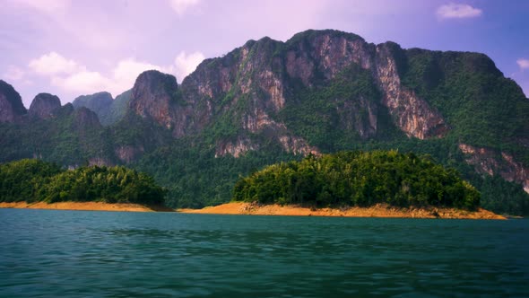 Sailing Past Small Islands On Cheow Lan Lake With View Of Limestone Cliffs At Khao Sok National Park alt