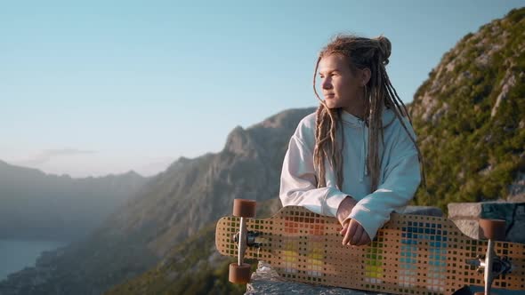 Peaceful dreadlocks woman longboarder  enjoying amazing view on sunset  mountain