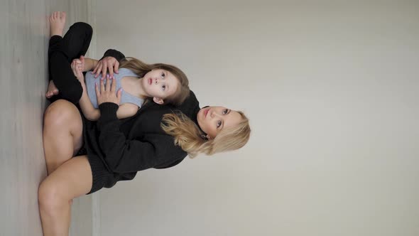 Photographer Takes Pictures Mother in a Black Sweater and a Jacket with Her Daughter at Photo Shoot alt