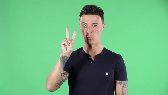 Portrait of a Handsome Young Guy Is Looking at Camera Shows and Counting One, Two, Three, Four, Five alt