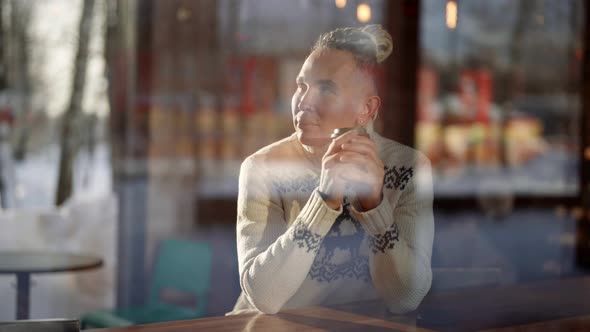 Man is Drinking Hot Coffee in Cafe After Walk in Cold Winter Day Resting in Cozy Coffee Shop alt