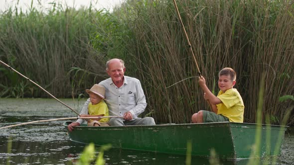 Active Childhood on River Grandfather with His Grandchildren are Fishing While Sitting in Boat alt