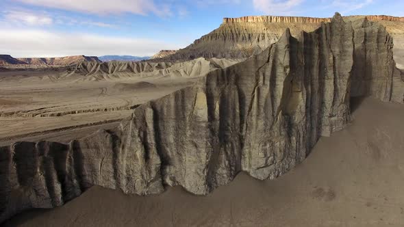 Flying over cliff spires revealing desert landscape covered in tire tracks alt
