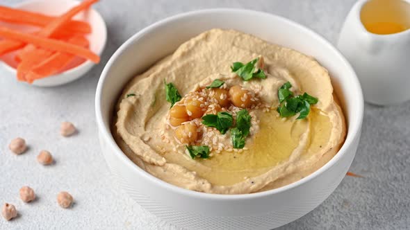 Eating hummus with carrot. hummus with sesame and olive oil. Healthy vegan food. Vegetarian dish.