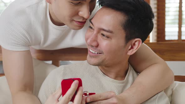 Young Asia gay couple propose at modern home, LGBTQ men happy smiling have romantic time.