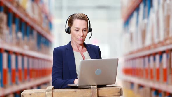 Female warehouse manager using laptop alt