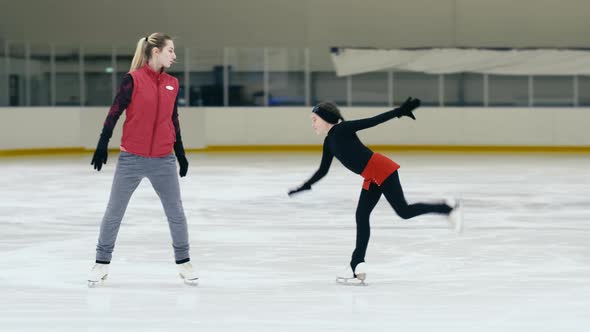 Figure skating trainer moving near trainee on ice