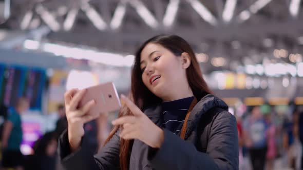 Pretty young traveller female using smartphone selfie at airport terminal
