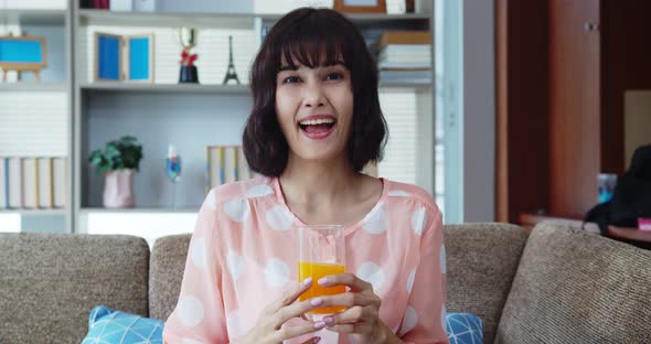 Asian young pretty woman drinking orange juice on sofa  alt