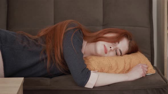 Sleepy red hair female student falls down on sofa. Exhausted, bored, apathetic girl.