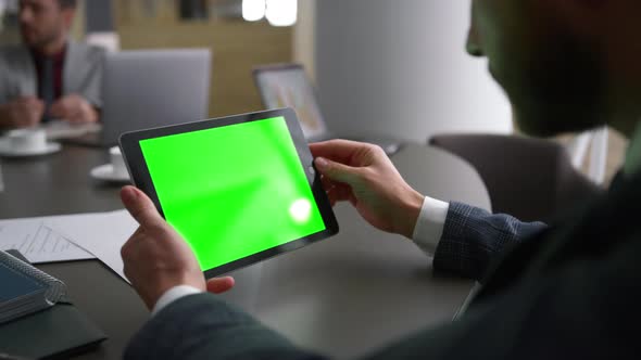 Businessman Using Tablet Device Green Screen Looking Corporate News in Workplace alt