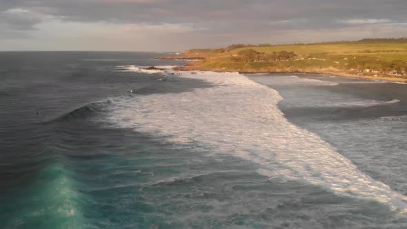 Surfers wait for the perfect wave and waves roll in to Maui Hawaii's Ho'okipa Beach at sunset. alt