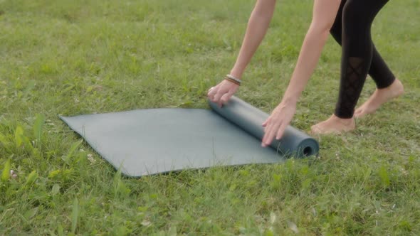 Closeup of of Hands Roll Out Yoga Mat Outdoors