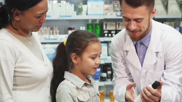 Friendly Pharmacist Shows Little Girl One of the Tubes alt