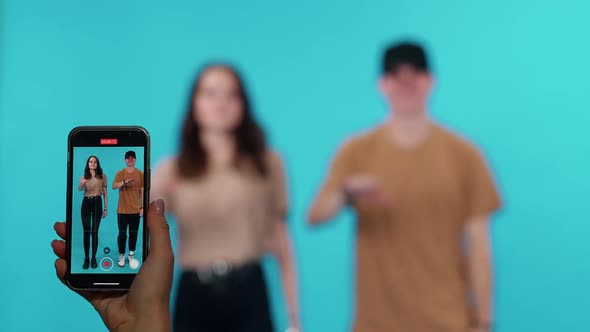 Young Guy and a Female are Dancing Merrily to the Music on a Blue Light Background While Shooting a alt