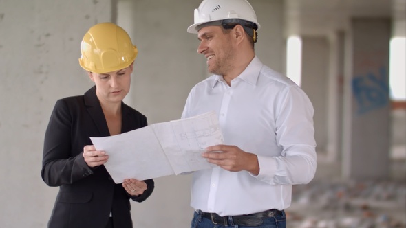Two architects wearing protective helmet works at building site