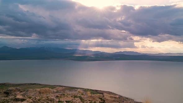 Storm clouds moving in the distance as light rays shine to the ground alt