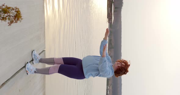 curly girl with red hair doing squats raising her hands in front of her alt
