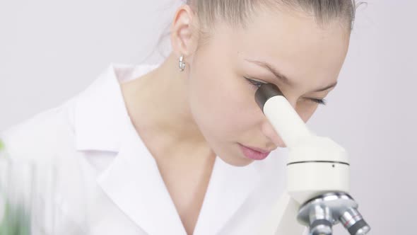 Closeup Pretty Gastroenterologist Works with Microscope on White Lab Background